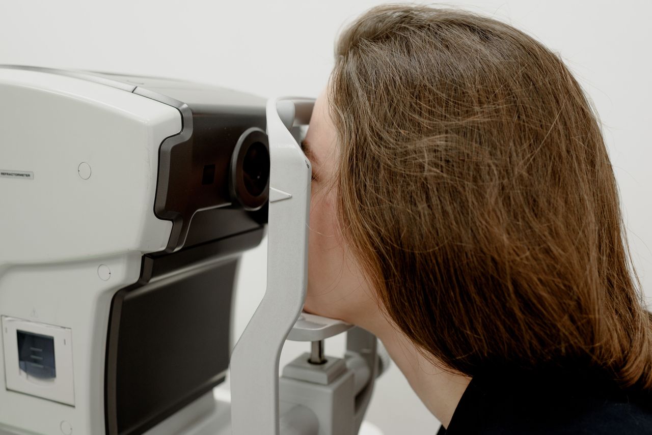 Side view of female client checking vision during medical treatment in ophthalmology clinic
