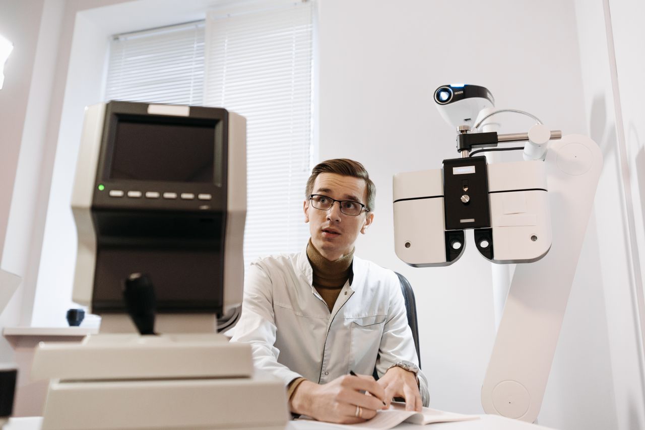 Optician in a clinic performing an eye examination with advanced vision testing equipment. Professional setting.